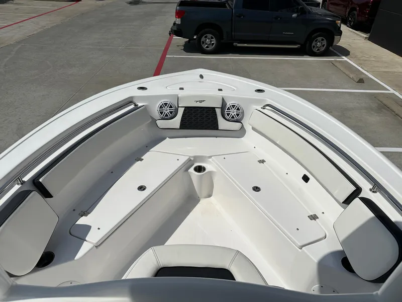 Slide: The Image of 2025 Tidewater 210CC boat interior with seating and speakers, parked in a lot. - 23