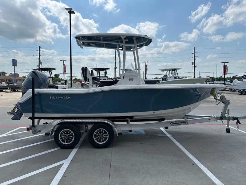 Slide: The Image of 2025 Tidewater 210CC boat on trailer, parked outdoors under a partly cloudy sky. - 7