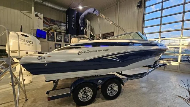 Slide: The Image of 2020 Crownline E 215 XS boat displayed indoors on a trailer. - 1