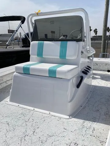 Slide: The Image of 2025 Majek 20 Xtreme boat with white and teal seating, docked under a clear sky. - 3