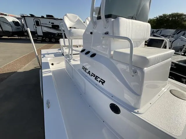 Slide: The Image of 2025 Majek 24 Reaper boat with white seating and console, parked near RVs. - 10