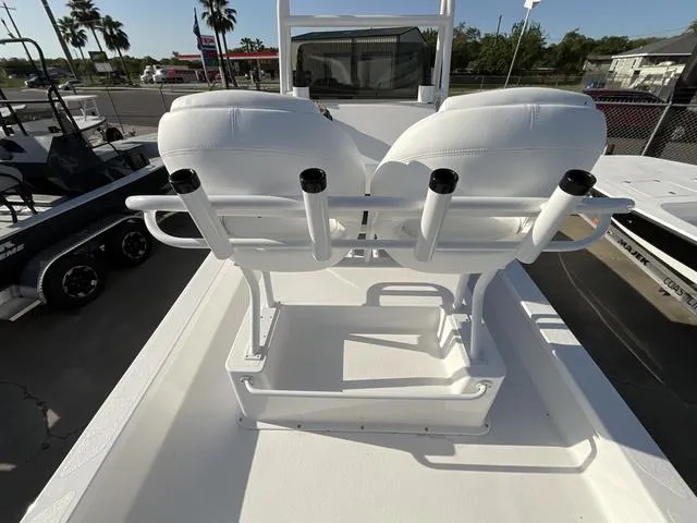 Slide: The Image of 2025 Majek 24 Reaper boat with white seating and rod holders, parked outdoors. - 13