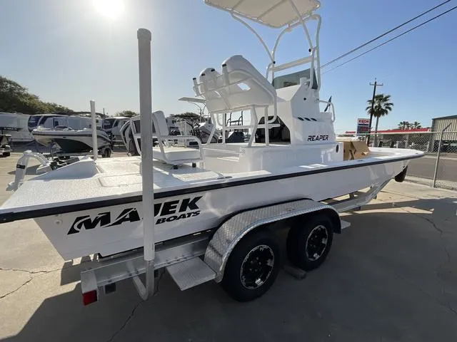 Slide: The Image of 2025 Majek 24 Reaper boat on trailer, white exterior, dual axles, sunny day. - 3