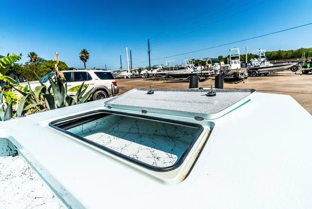 Slide: The Image of 2025 Majek 2206 Illusion boat hatch open, showcasing storage area in sunny marina setting. - 16