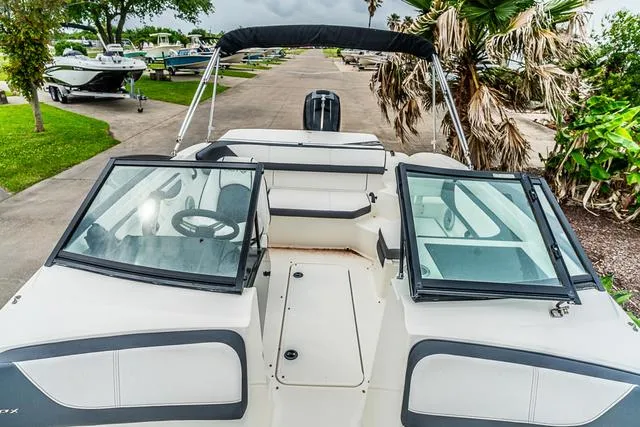 Slide: The Image of 2015 Sea Ray 19spx OB boat with open deck, windshield, and lush surroundings. - 19