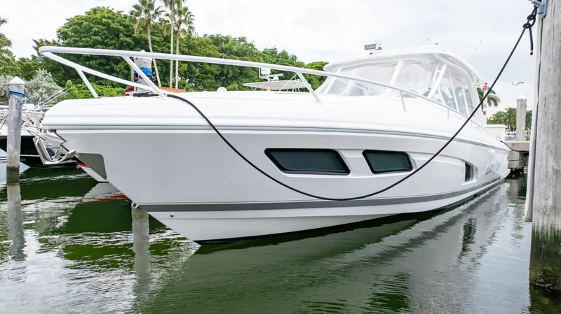 Slide: The Image of 2022 Intrepid 409 Valor boat docked in marina, sleek white design, calm water reflection. - 26