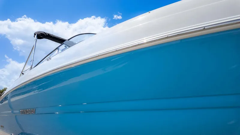 Slide: The Image of 2025 Stingray 211DC boat with blue hull under a clear sky. - 3