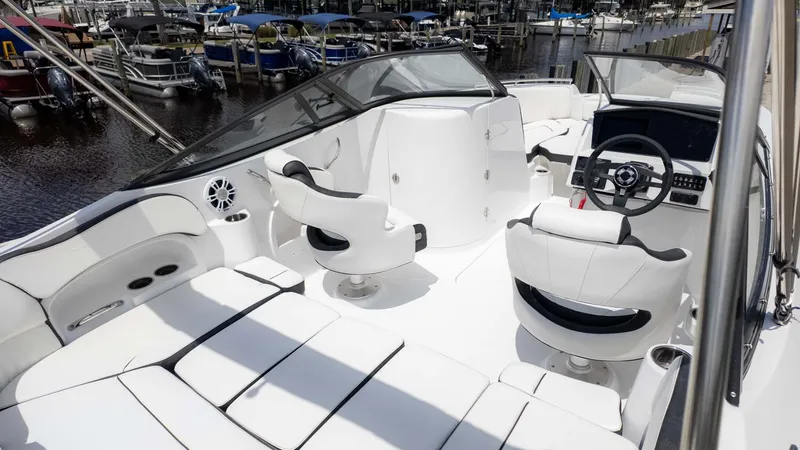 Slide: The Image of 2025 Stingray 211DC boat interior with white seating and modern dashboard, docked at marina. - 7