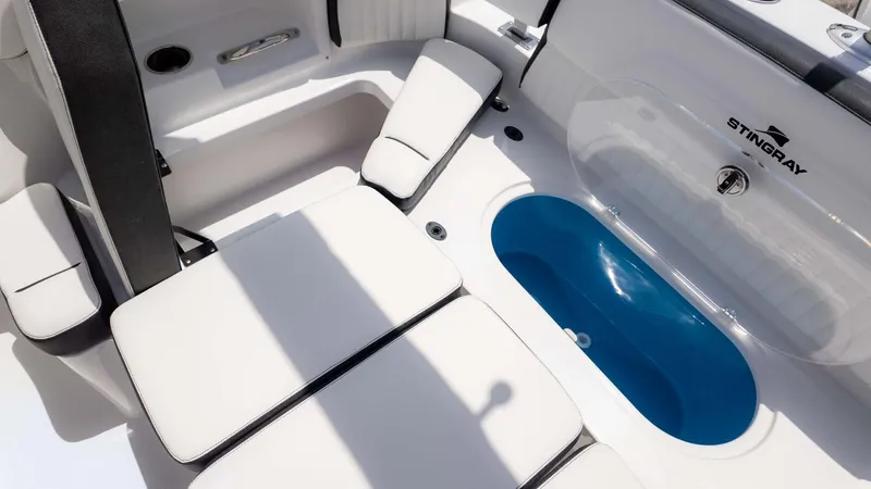 Slide: The Image of 2025 Stingray 211DC boat interior with white seating and blue storage compartment. - 9