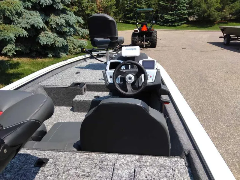 Slide: The Image of 2025 Tracker Pro Team 175 boat interior with steering wheel and seating, parked outdoors. - 5