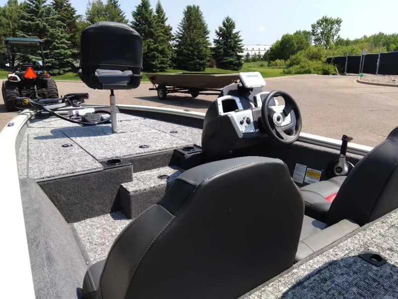 Slide: The Image of 2025 Tracker Pro Team 175 boat interior with steering wheel and seating, parked outdoors. - 6