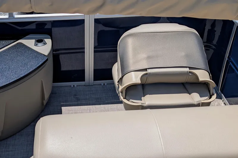 Slide: The Image of 2025 Sun Tracker Fishin' Barge 20 DLX interior with beige seating and storage. - 6