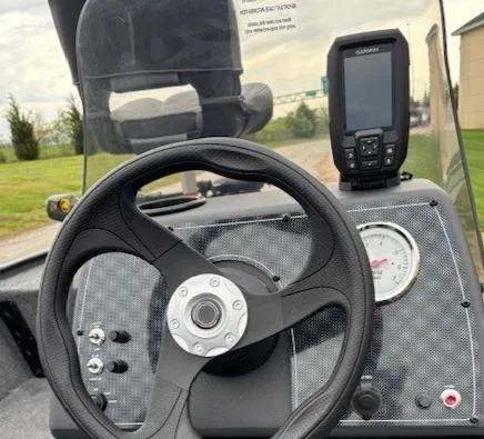 Slide: The Image of 2025 Tracker Bass Tracker Classic XL dashboard with steering wheel and Garmin device. - 2