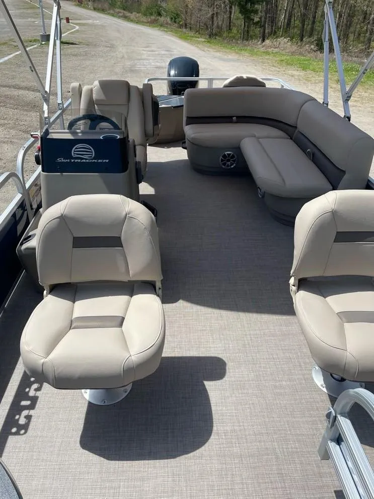 Slide: The Image of 2025 Sun Tracker Bass Buggy 18 DLX pontoon boat interior with beige seating and spacious layout. - 2