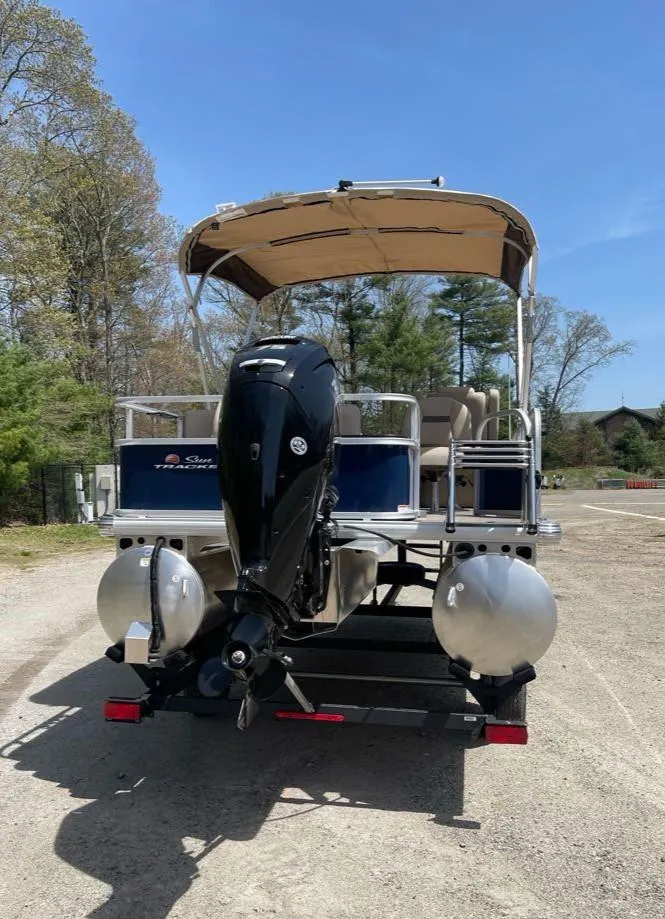 Slide: The Image of 2025 Sun Tracker Bass Buggy 18 DLX pontoon boat with outboard motor, parked outdoors. - 6