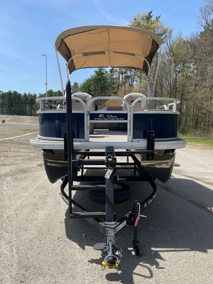 Slide: The Image of 2025 Sun Tracker Bass Buggy 18 DLX pontoon boat on trailer, parked outdoors. - 7