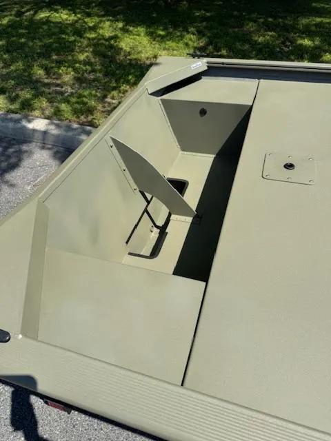 Slide: The Image of 2025 Tracker Grizzly 1648 Jon boat, open storage compartment, green finish, outdoor setting. - 4