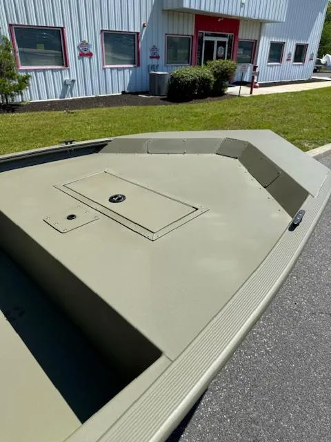 Slide: The Image of 2025 Tracker Grizzly 1648 Jon boat, olive green, parked outside a building. - 6