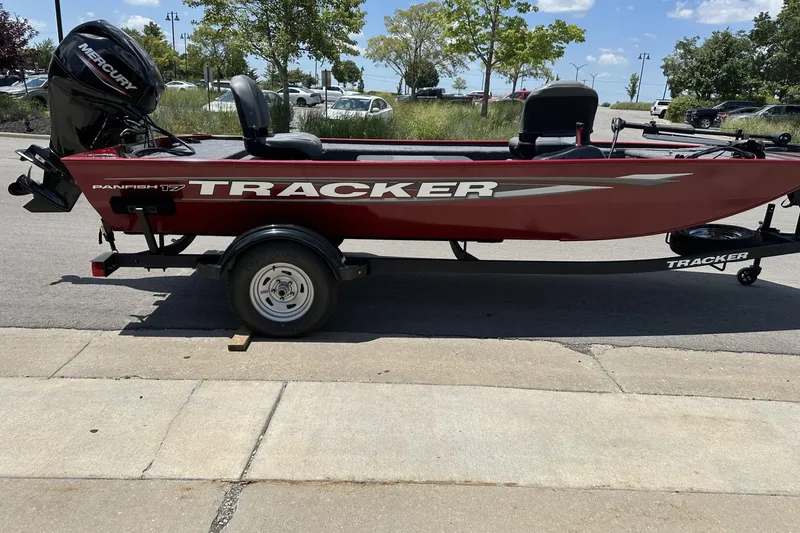 Slide: The Image of 2025 Tracker Panfish 17 boat with Mercury engine on a trailer, parked outdoors. - 4