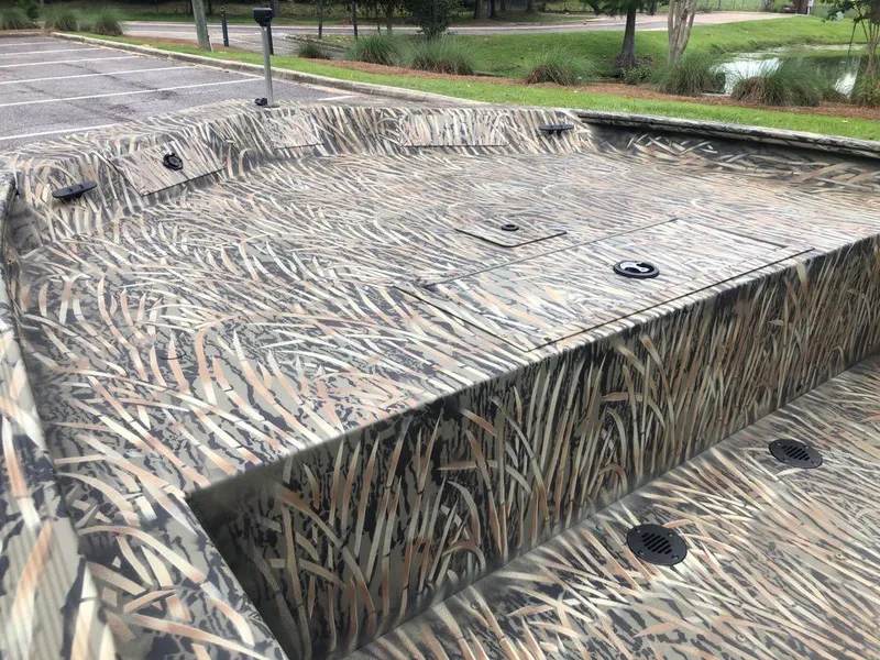 Slide: The Image of 2025 Tracker Grizzly 1860 CC boat with camouflage pattern in a parking area. - 9