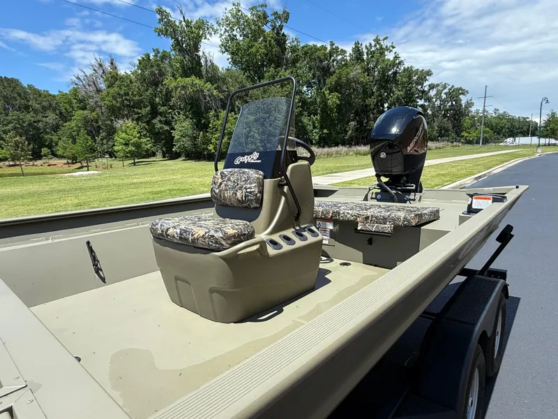 Slide: The Image of 2025 Tracker Grizzly 2072 CC boat with camo seats on a trailer, parked outdoors. - 2