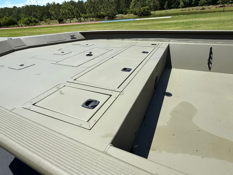 Slide: The Image of 2025 Tracker Grizzly 2072 CC boat deck with storage compartments, outdoors. - 7