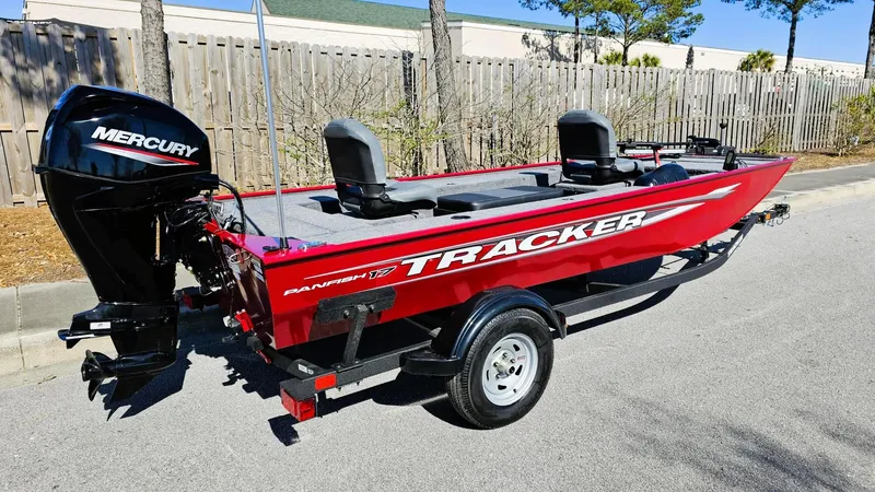 Slide: The Image of 2025 Tracker Panfish 17 boat with Mercury engine, red color, parked on street. - 2