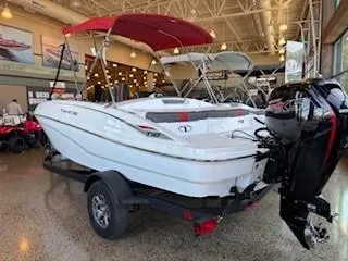 Slide: The Image of 2025 Tahoe T18 boat with red canopy displayed indoors on a trailer. - 1