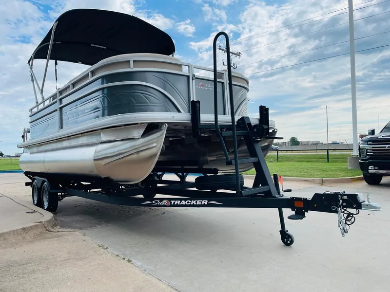 Slide: The Image of 2025 Sun Tracker Party Barge 20 DLX pontoon boat on trailer, parked outdoors. - 3