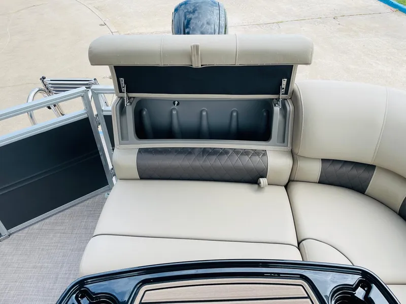 Slide: The Image of 2025 Sun Tracker Party Barge 20 DLX interior with open storage compartment and cushioned seating. - 32