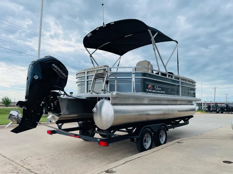 Slide: The Image of 2025 Sun Tracker Party Barge 20 DLX pontoon boat on trailer, with canopy and outboard motor. - 5
