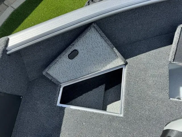 Slide: The Image of 2024 Lund 1775 Impact XS Sport boat interior storage compartment, gray carpeted finish. - 24