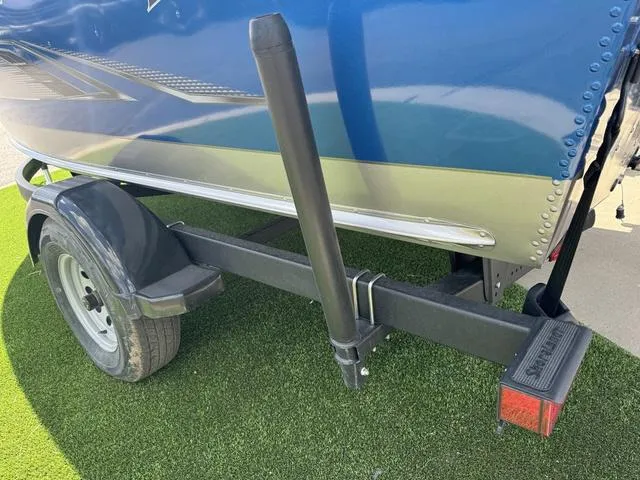 Slide: The Image of 2024 Lund 1775 Impact XS Sport boat trailer, featuring a blue and silver design on grass. - 7