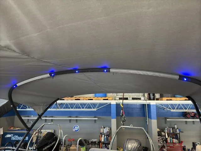 Slide: The Image of 2025 Bennington 22ML Cruise boat canopy with blue LED lights in a workshop. - 24