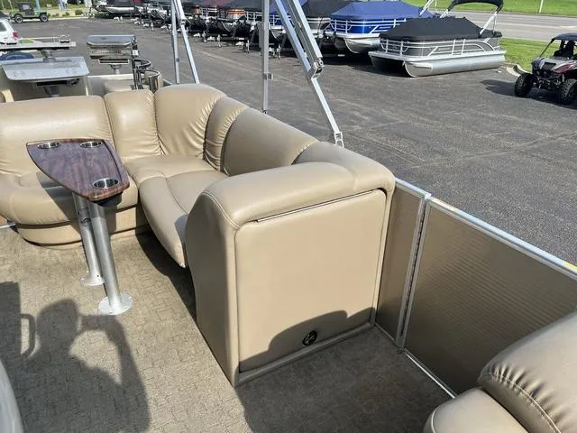Slide: The Image of 2015 Godfrey 2500 FE BAR pontoon boat with beige seating and table, parked near other boats. - 11