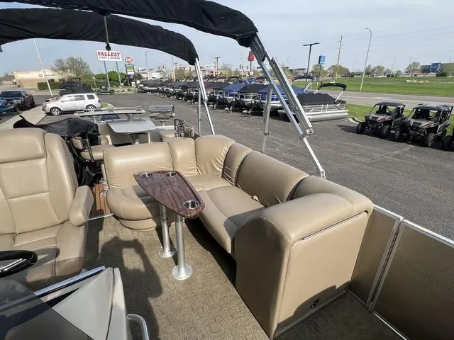 Slide: The Image of 2015 Godfrey 2500 FE BAR pontoon boat with beige seating and table, parked outdoors. - 12