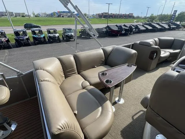 Slide: The Image of 2015 Godfrey 2500 FE BAR pontoon boat with plush seating and cupholders, parked near vehicles. - 14