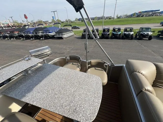 Slide: The Image of Pontoon boat with granite-style table, seating, and grill, parked near other boats and vehicles. - 16