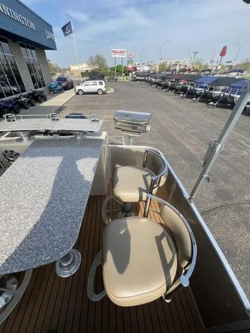 Slide: The Image of 2015 Godfrey 2500 FE BAR boat with bar seating and table, parked at dealership. - 17