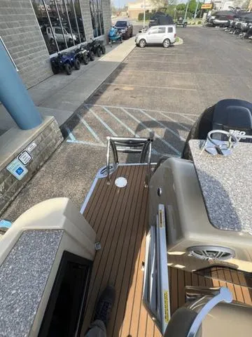 Slide: The Image of 2015 Godfrey 2500 FE BAR boat parked near a dealership, showcasing deck and seating area. - 20