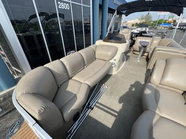 Slide: The Image of 2015 Godfrey 2500 FE BAR pontoon boat with beige seating and canopy, docked near a building. - 8
