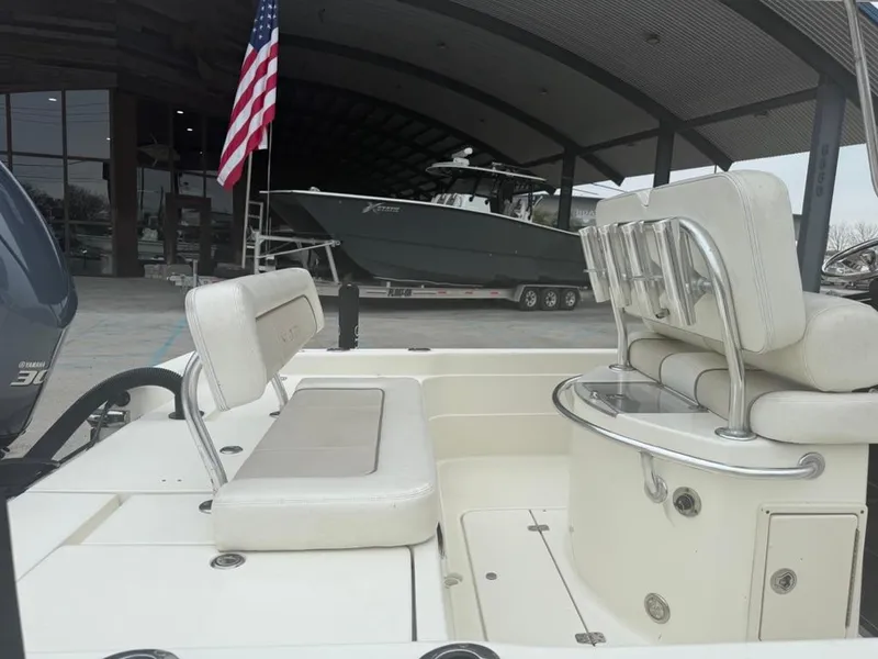 Slide: The Image of 2012 ShearWater 25LTZ boat interior with seating, American flag, and showroom background. - 13