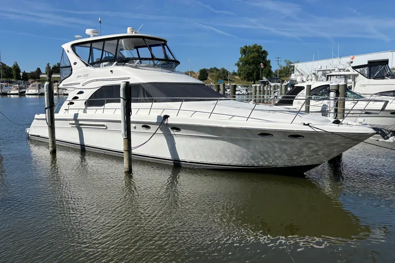The Image of 2002 Sea Ray 560 Sedan Bridge yacht docked in a marina under clear blue skies. - 0