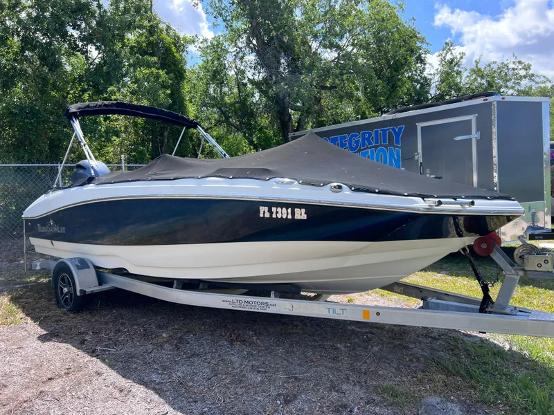 The Image of 2017 NauticStar 203SC Sport Deck boat on trailer, covered, parked outdoors. - 0