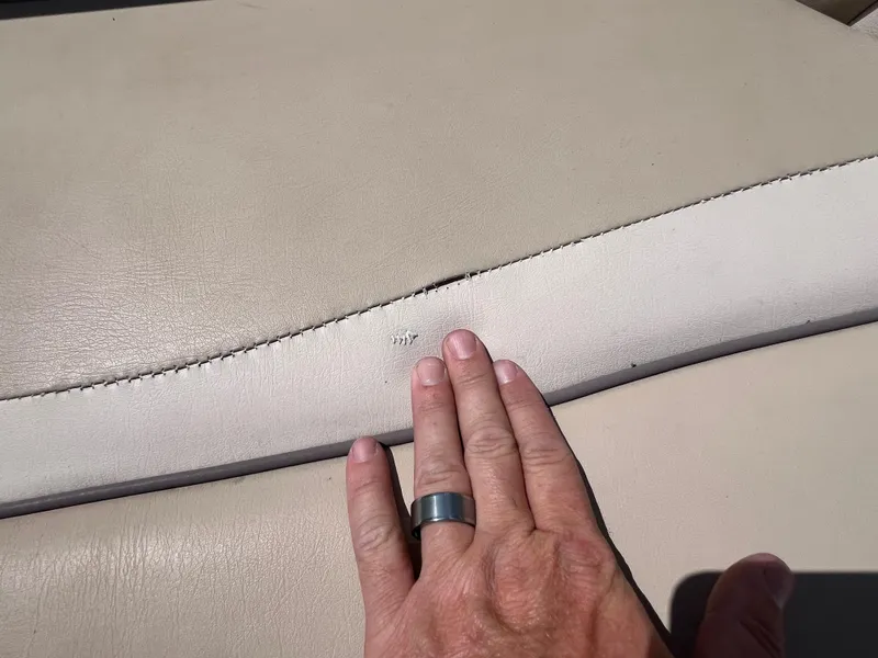 Slide: The Image of Close-up of a hand touching beige upholstery on a 2017 NauticStar 203SC Sport Deck. - 23