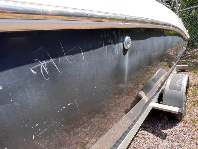 Slide: The Image of 2017 NauticStar 203SC Sport Deck boat with visible scratches on the black hull. - 28
