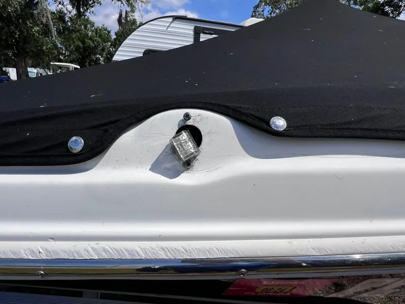 Slide: The Image of 2017 NauticStar 203SC Sport Deck boat with black cover and visible light fixture. - 29