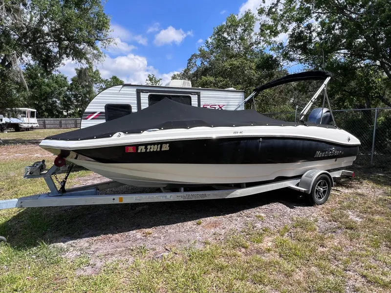 Slide: The Image of 2017 NauticStar 203SC Sport Deck boat on trailer, parked outdoors near RV. - 4