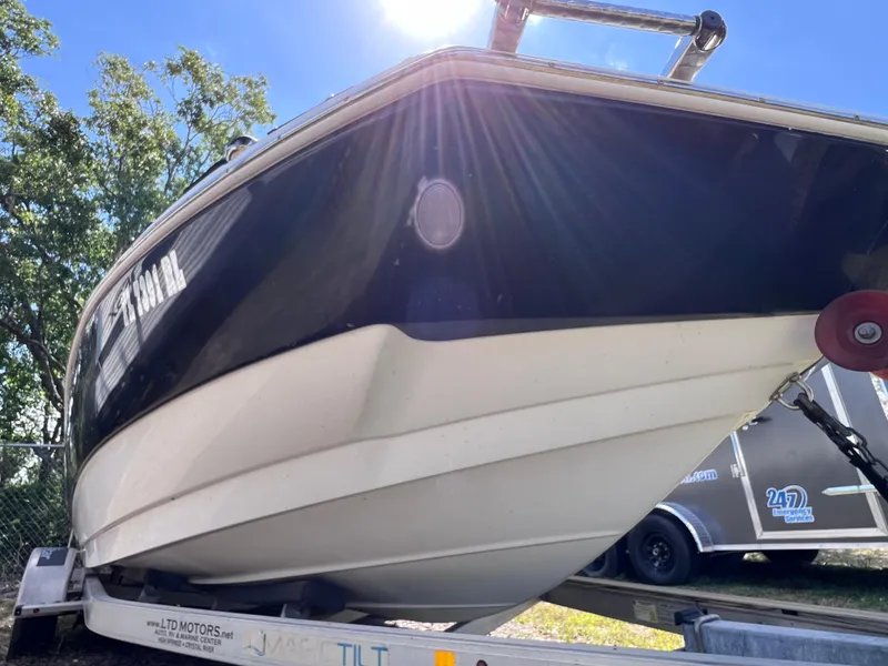 Slide: The Image of 2017 NauticStar 203SC Sport Deck boat on trailer, sunlit, with trees in background. - 7