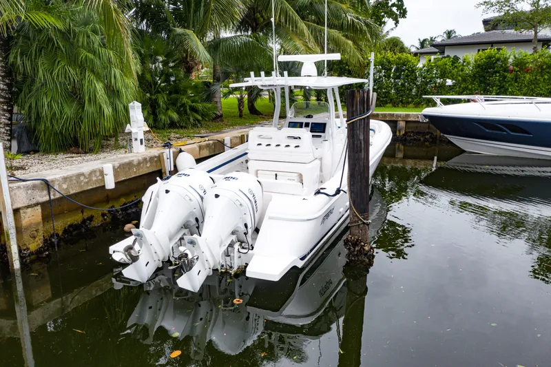 Slide: The Image of 2018 Intrepid 327 Center Console boat docked with twin engines, surrounded by lush greenery. - 10